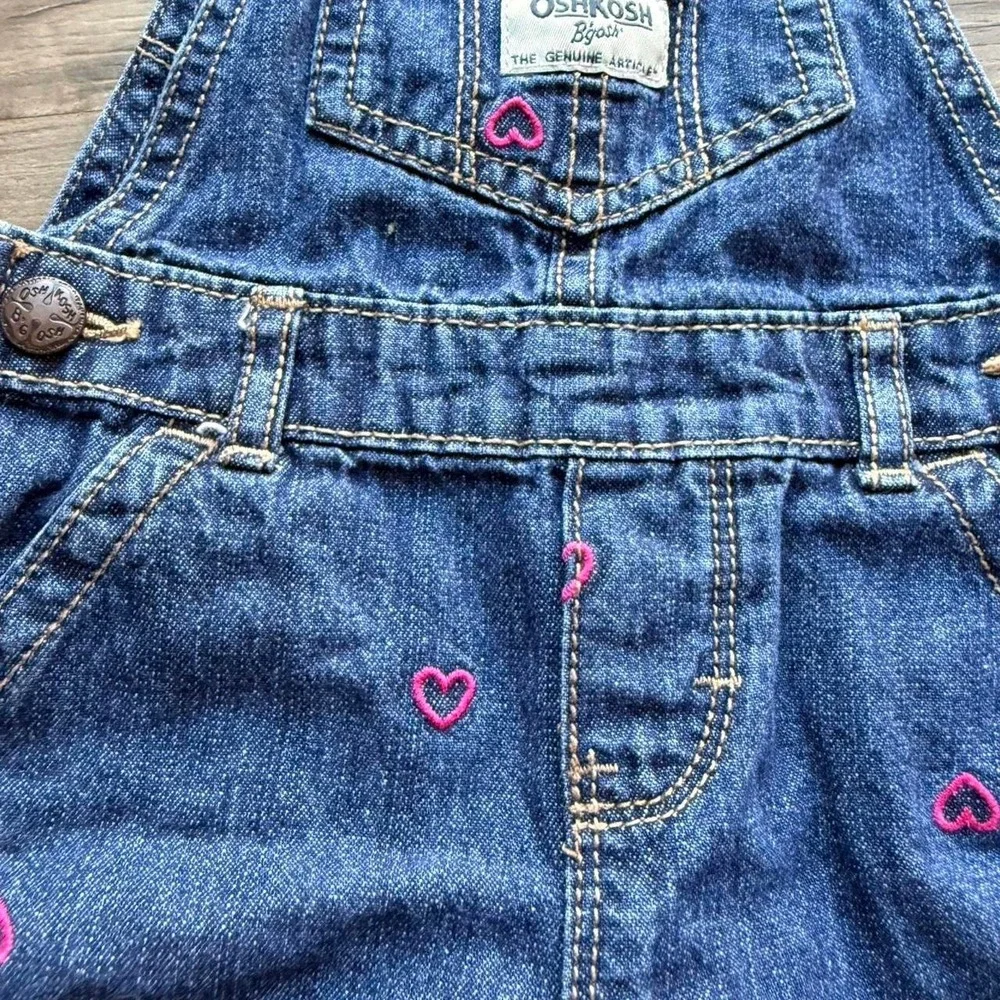 OshKosh B'gosh blue denim overalls with pink heart embroidery